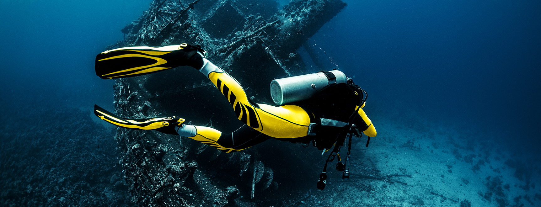 Scuba diver passing by a wreckage of a large sunken ship in the Red Sea.