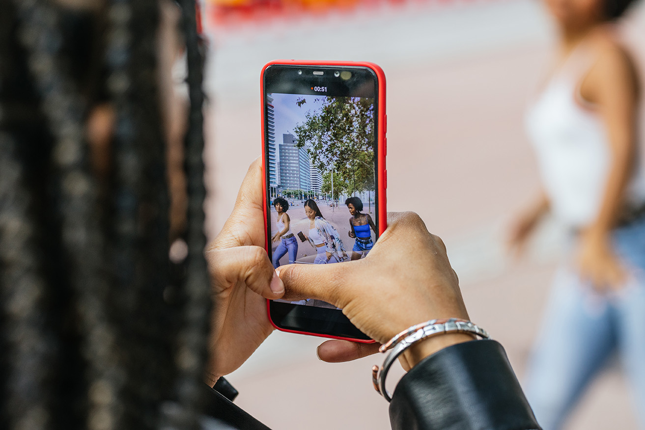 Close-up of the mobile screen while women recording a video dancing in the street