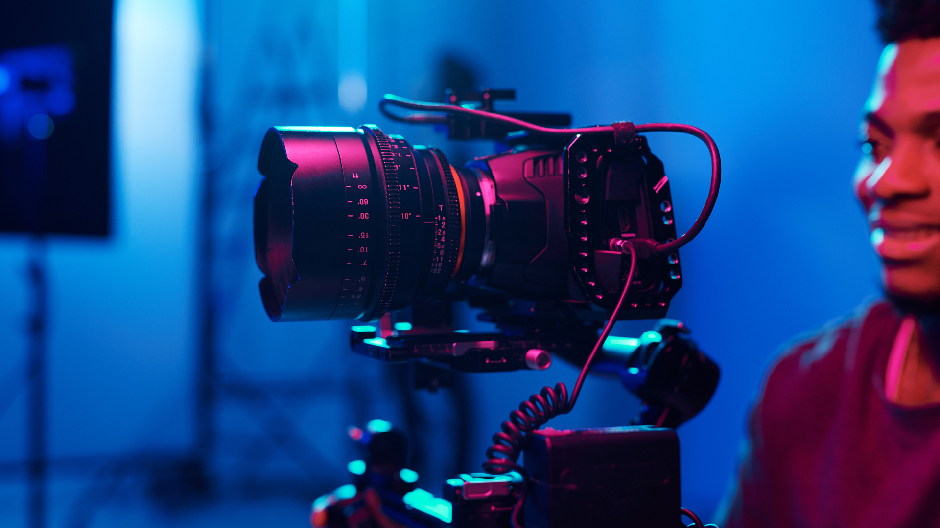 a young black man standing behind a hgh-end digital video camera.